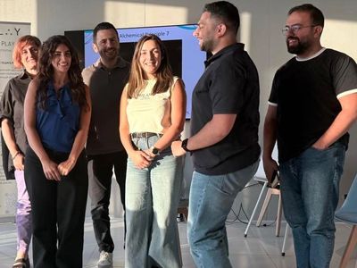 Group of six people standing and smiling indoors.