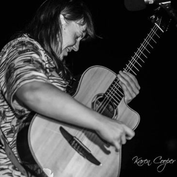 Musician passionately playing acoustic guitar in a black and white photo.