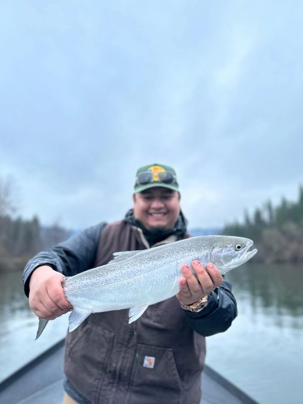 Smiling man holding a freshly caught fish on a boat.