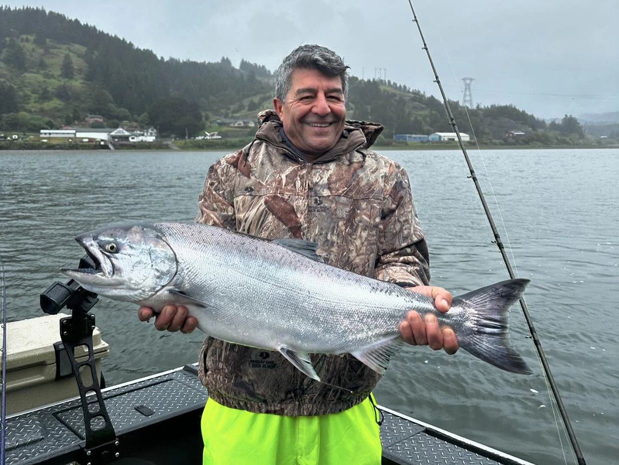 Man proudly holding a large fish on a boat.