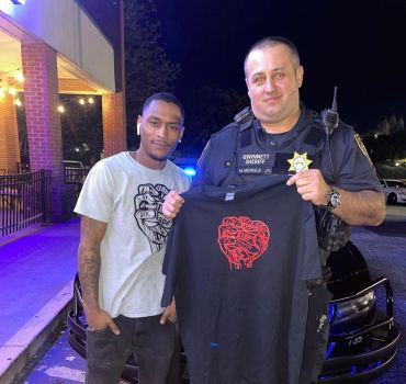 A man and a sheriff posing with a heart-themed t-shirt at night.