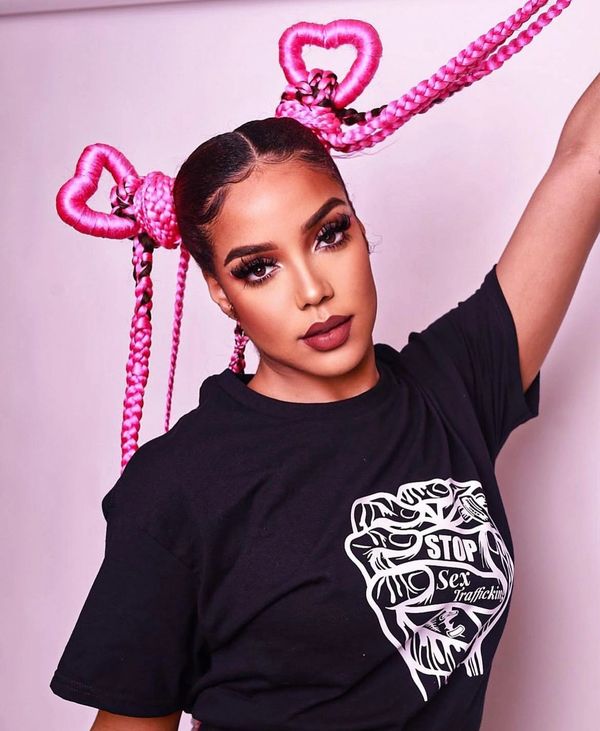 Woman with bright pink heart-shaped braided hair and a black t-shirt against sex trafficking.