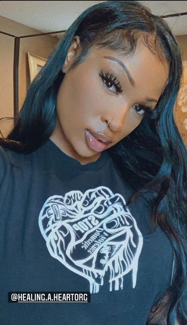Young woman with long black hair wearing a shirt promoting non-violence.