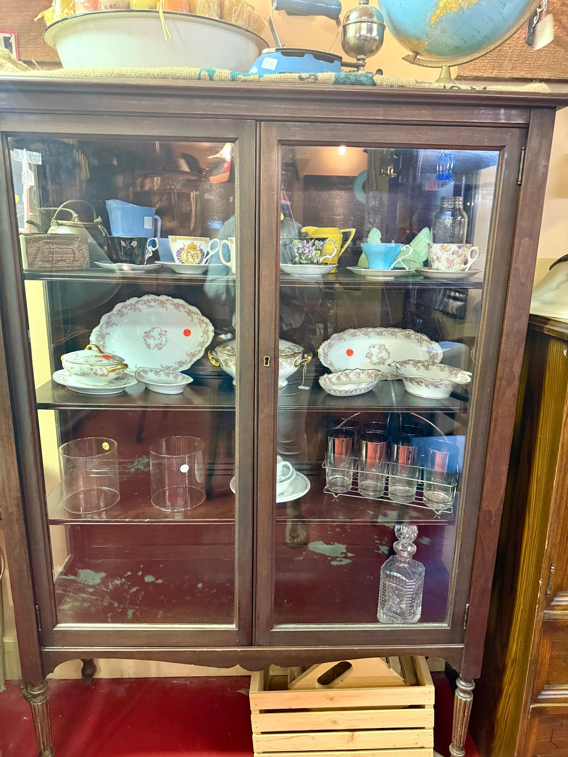 Antique wooden cabinet with vintage teacups and dishes.
