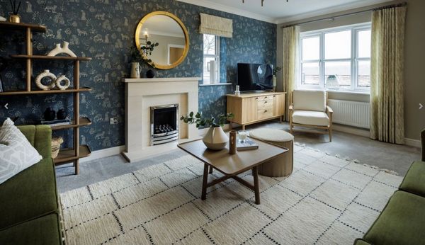 Stylish new build living room with feature wallpaper, fireplace, and modern green sofa set.