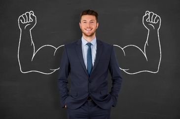 Confident businessman posing with drawn muscular arms on chalkboard.