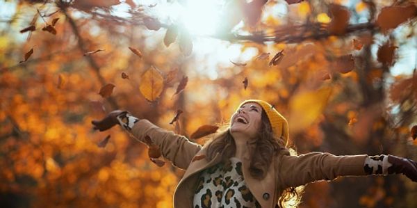 Woman, arms open, looking up at the Fall sky