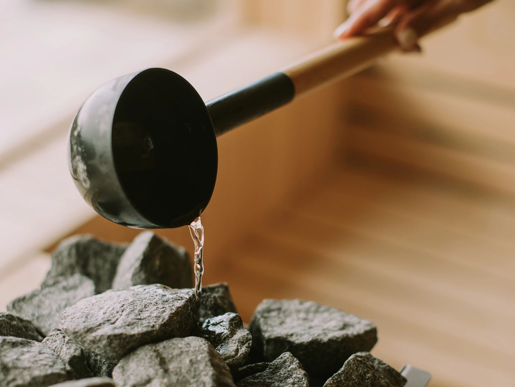 Pouring water onto sauna stones with a ladle.