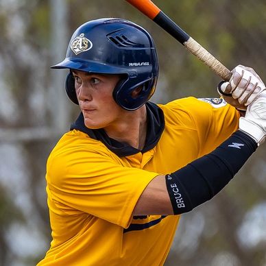 Baseball player in yellow jersey preparing to bat.