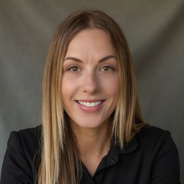Smiling woman with straight blonde hair in a black shirt against a gray background.