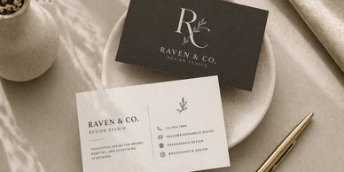 Elegant Raven &amp; Co. design studio business cards on a soft fabric background.