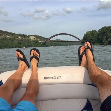 Two men wearing black flip flops on a boat