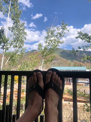 A person wearing black flip flops on his balcony