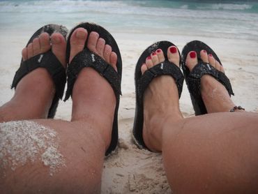 Man and woman wearing black flip flops on the beach
