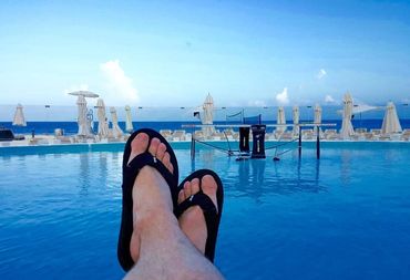 A person wearing black sandals on a pool