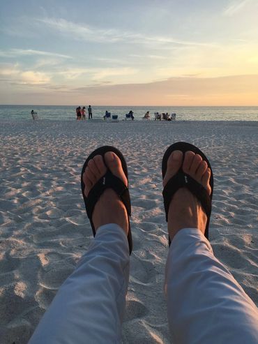 A person wearing black sandals on the beach