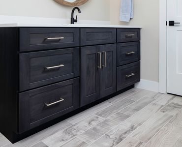 Dark wooden bathroom cabinet with silver handles and a white countertop.