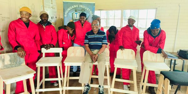 Group of workers in red uniforms with wooden chairs.