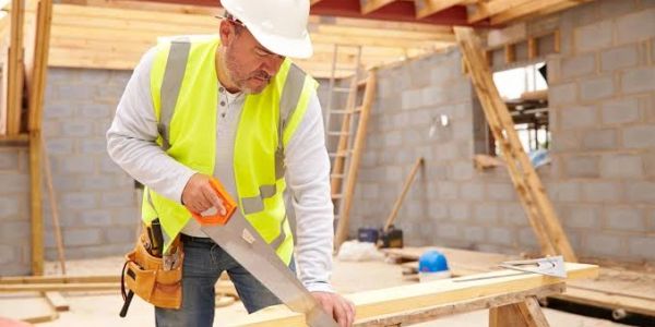 Construction worker cutting wood inside a building.