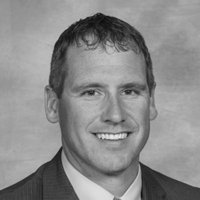 Black and white portrait of a smiling man in a suit and tie.