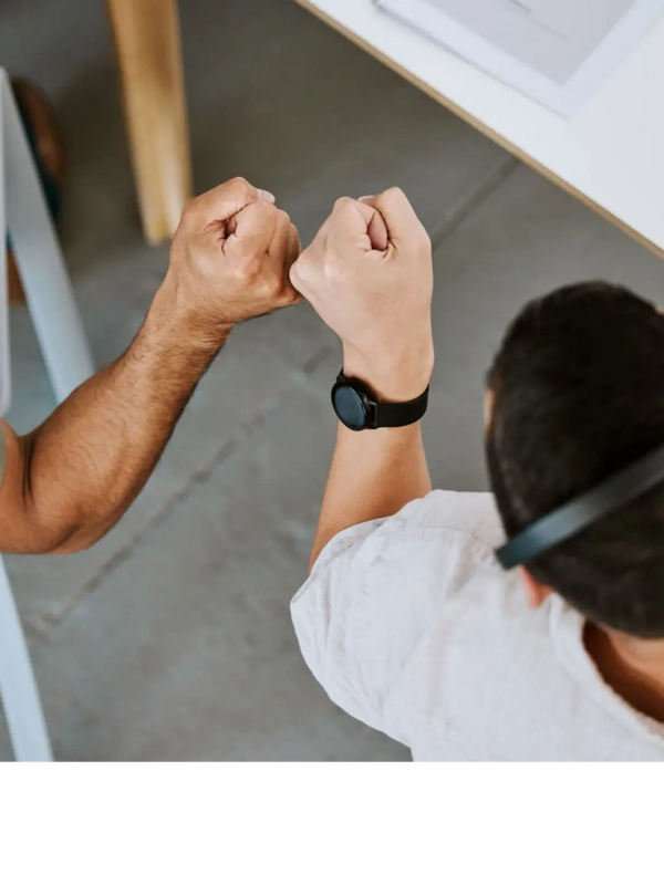 Two people giving a fist bump in an office setting.