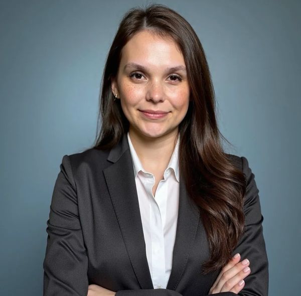 Confident woman in a black blazer with arms crossed, smiling.