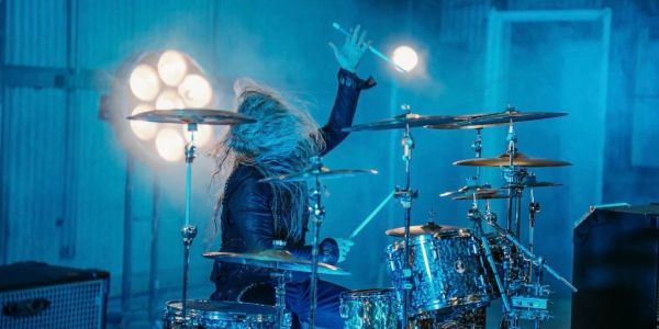 Drummer passionately playing drums with energetic hair movement.