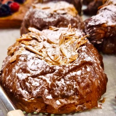 Close-up of almond croissants dusted with powdered sugar on display.