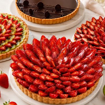 Three beautifully arranged fruit and chocolate tarts on plates.