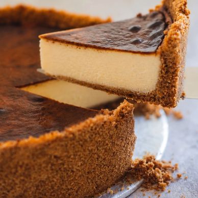 Close-up of a creamy cheesecake slice being lifted from a whole cheesecake.