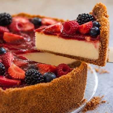 Slice of cheesecake topped with mixed berries and strawberry glaze.