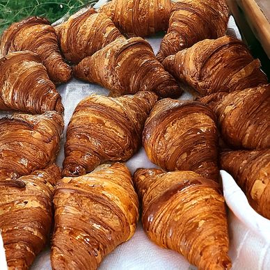 Golden, crispy croissants arranged on a white cloth.