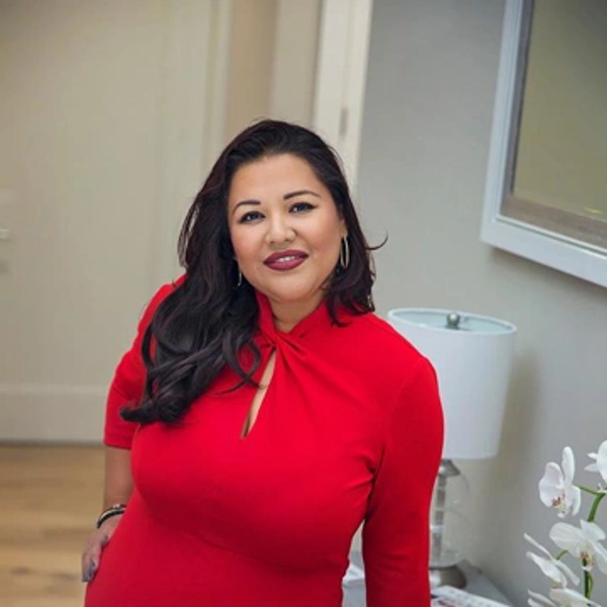 Woman smiling in a red dress indoors.
