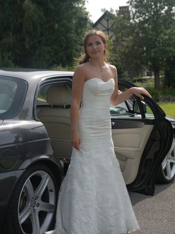 Bride standing next to a wedding car