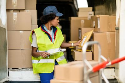 A worker in a safety vest organizes packages inside a delivery van.