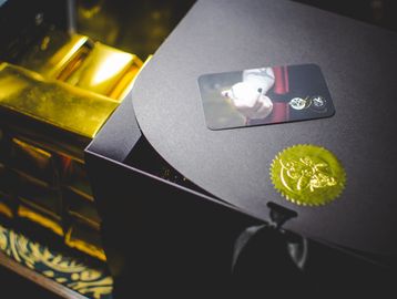 Elegant black box with a gold seal and a photo card on top.