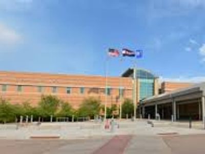 A large brick building with three flags flying in front under a clear blue sky.