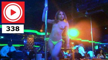 A woman pole dancing in a nightclub with neon lights and an audience.