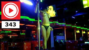 A woman dancing on a pole in a dimly lit club with neon lights.