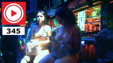 Women in revealing outfits sitting in a dimly lit bar or club.