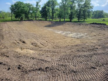 Large area of cleared, bare earth surrounded by trees.