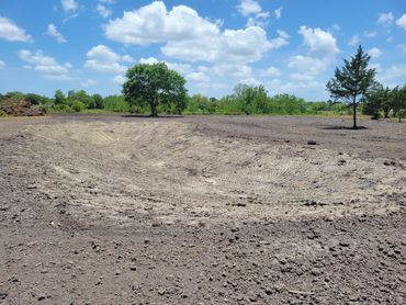 Cleared, bare earth under a partly cloudy sky.