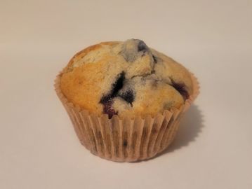 A blueberry muffin on a plain surface.
