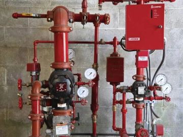 Red industrial piping system with gauges and control box.