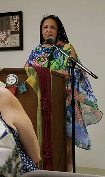 Woman speaking at a podium in a colorful dress.