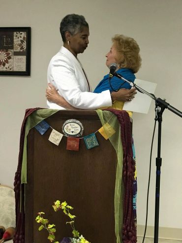 Two women embracing behind a decorated podium.