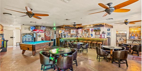 Casual bar with pool table and seating area under wooden ceiling fans.