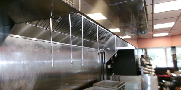A commercial kitchen with stainless steel grills and exhaust hoods.