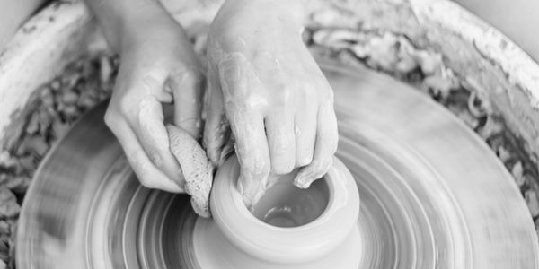 Hands shaping clay on a pottery wheel.