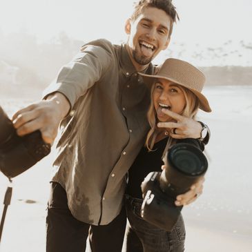 husband and wife photographer team is having fun and sticking their tongues out at the camera